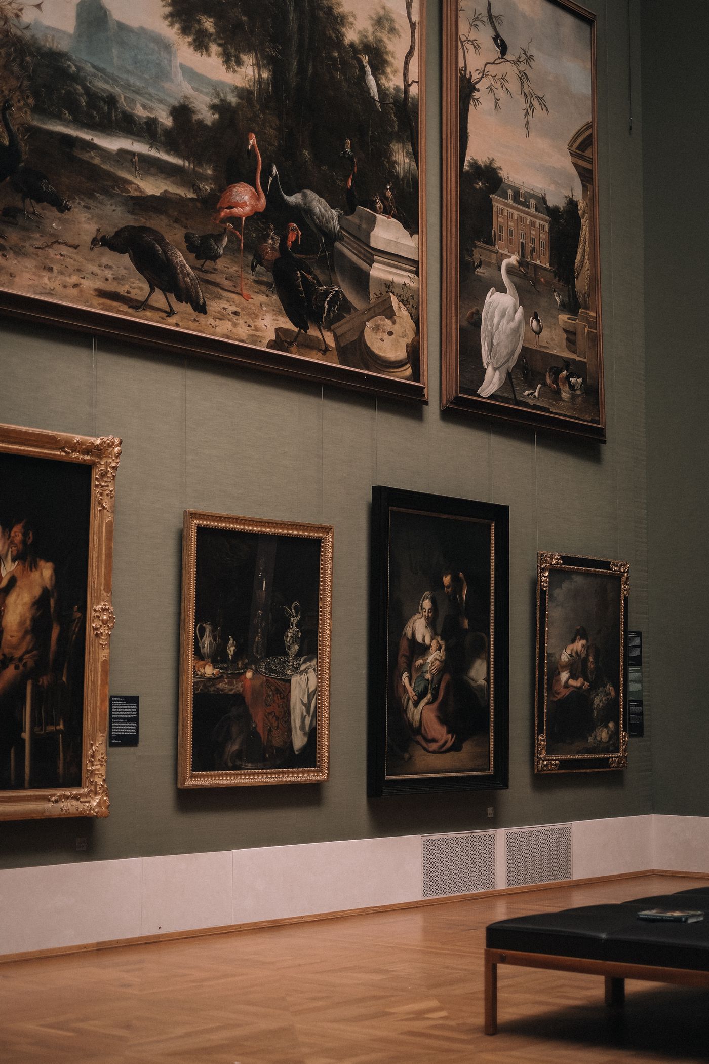 Old master paintings on a green gallery wall